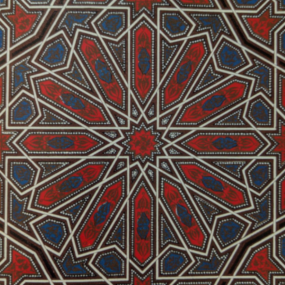 Intricate geometric design featuring red and blue motifs with white outlines, forming a star pattern on a dark background.