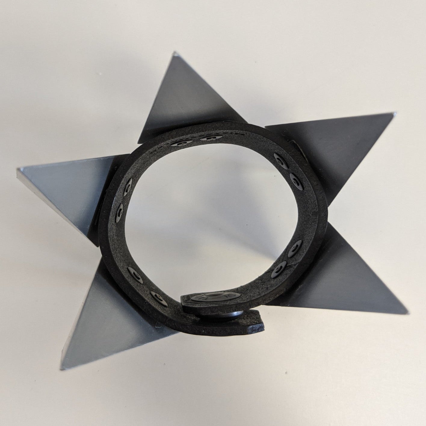 A star-shaped object with sharp metallic points attached to a circular black base, resembling a decorative or functional design.