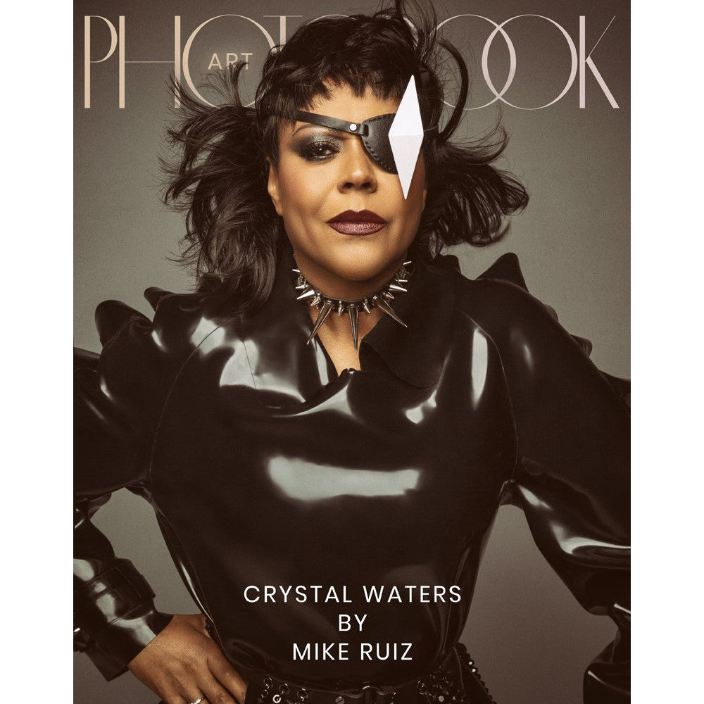 A fashion magazine cover featuring a model in a glossy black outfit with a spiked collar and eyepatch, emphasizing bold style and elegance.