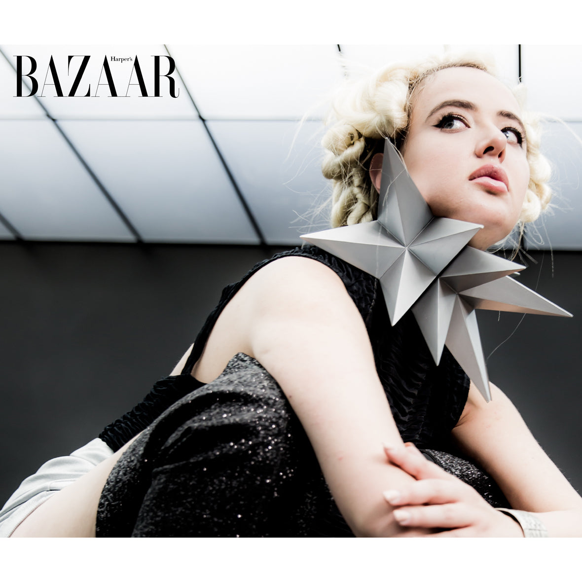 A fashion model showcases a striking neck piece and cuff bracelet against a modern interior backdrop, highlighting avant-garde design.