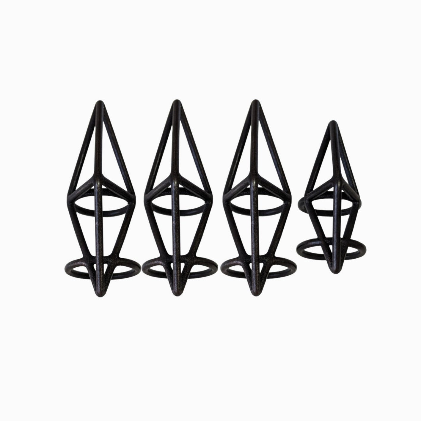Four metallic black geometric rings of varying sizes, each shaped like a diamond on a circular base, arranged in a row.