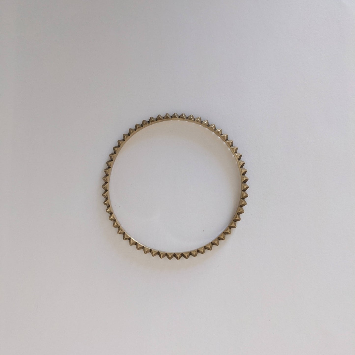 Brass bracelet with a textured design on a white background.