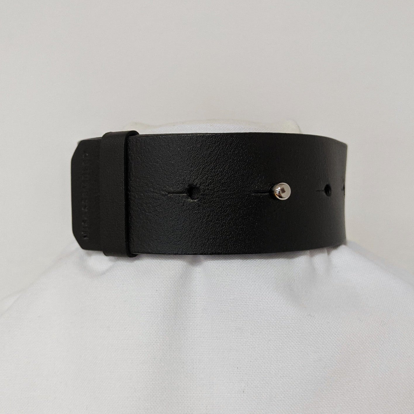 Black leather band with a smooth finish, featuring evenly spaced holes and a silver snap closure. Displayed on a white background.