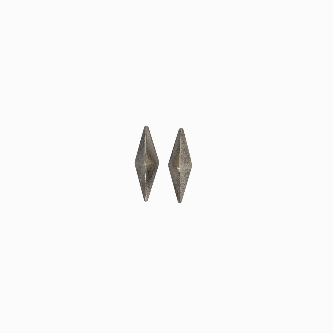A pair of silver geometric earrings shaped like elongated diamonds against a white background.