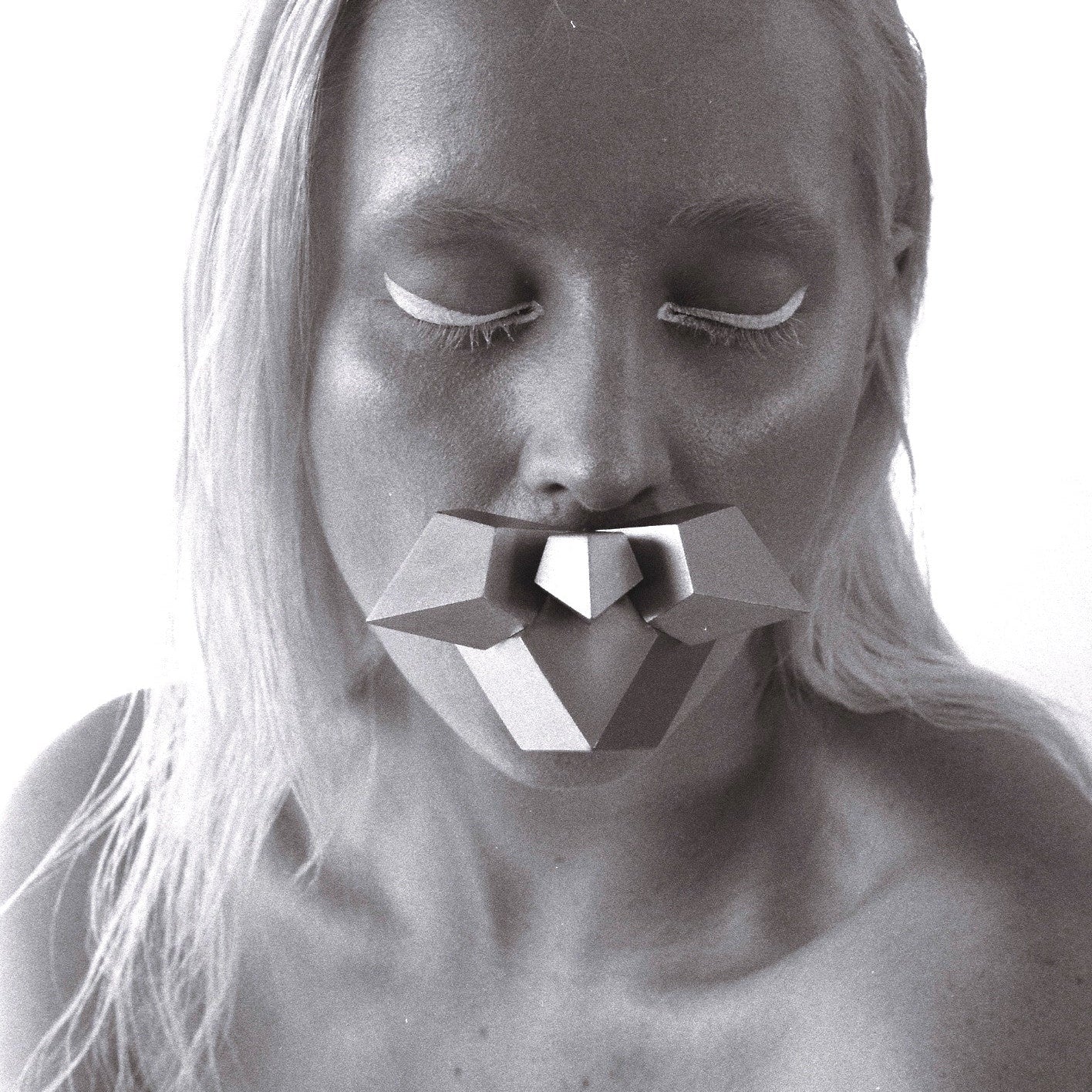 A close-up of a person with long, straight hair, showcasing their bare shoulders and holding a geometric shape in her mouth in a high-contrast black-and-white style.