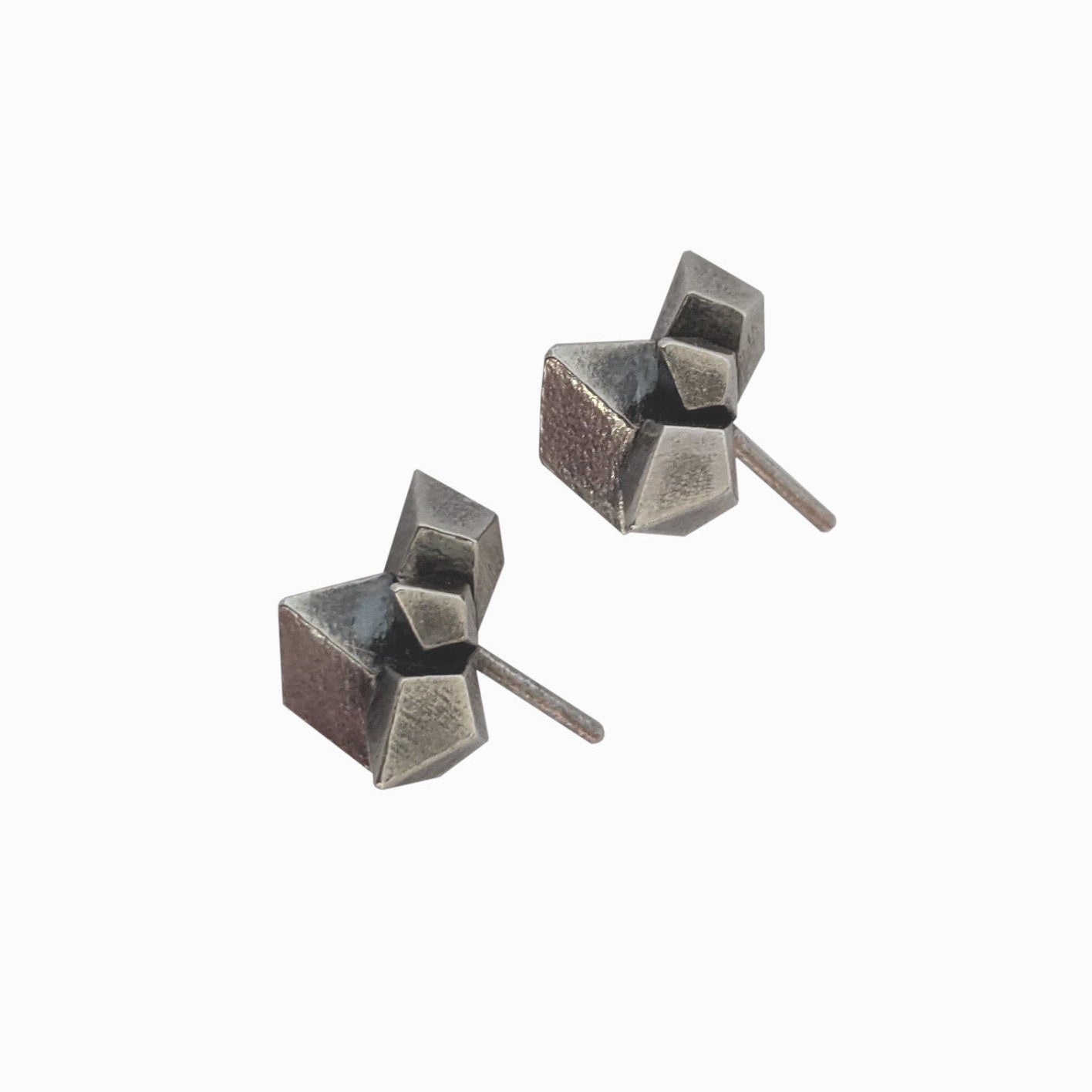A pair of geometric silver earrings with textured surfaces and angular shapes, resting on a white background.