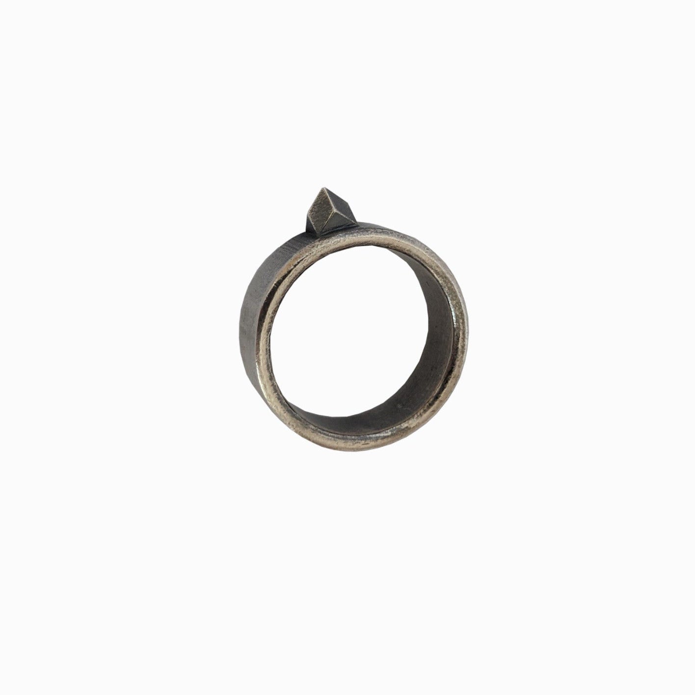 A minimalist metal ring featuring a geometric pyramid-shaped accent on top, set against a clean white background.