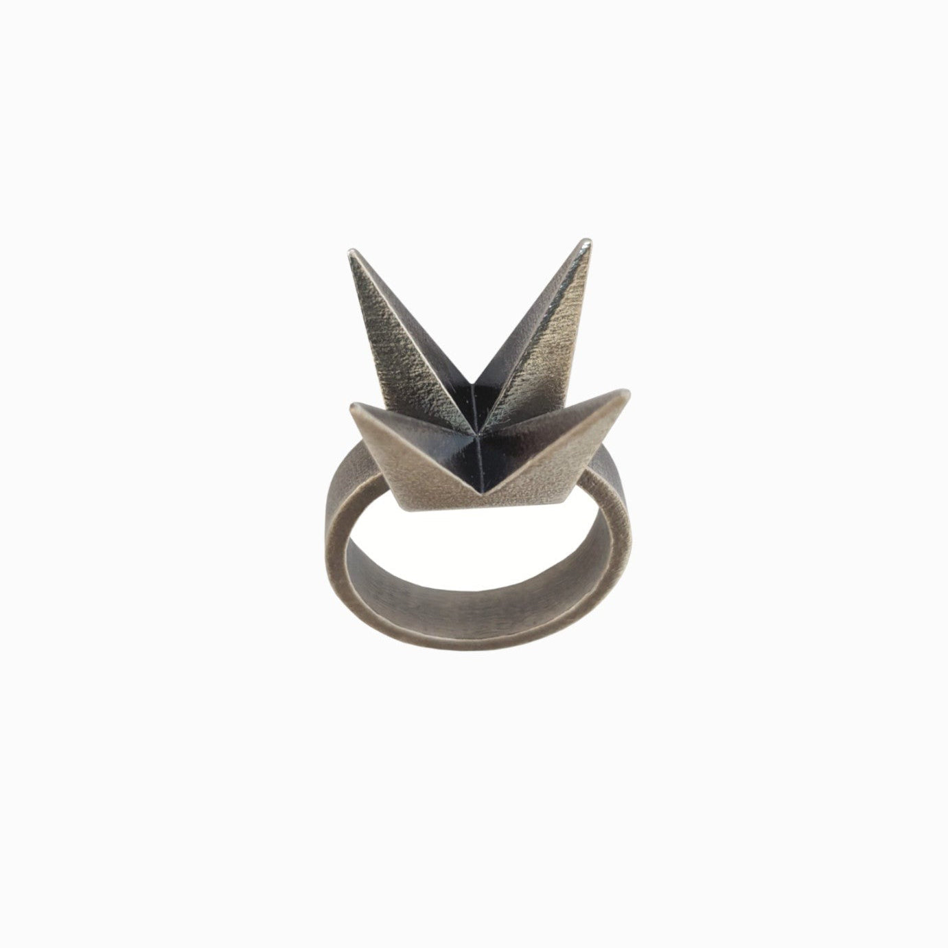 A unique geometric ring featuring two pointed, origami-inspired peaks in a matte metallic finish.