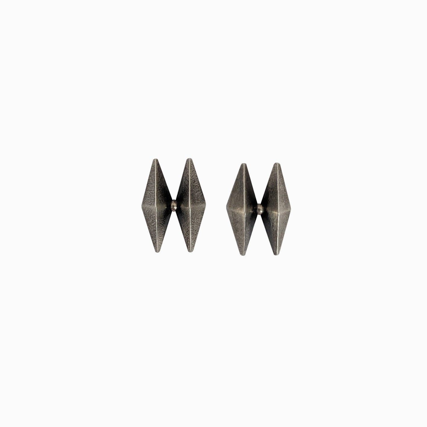 Metallic geometric earrings featuring a modern diamond shape design in a dark finish, set against a white background.