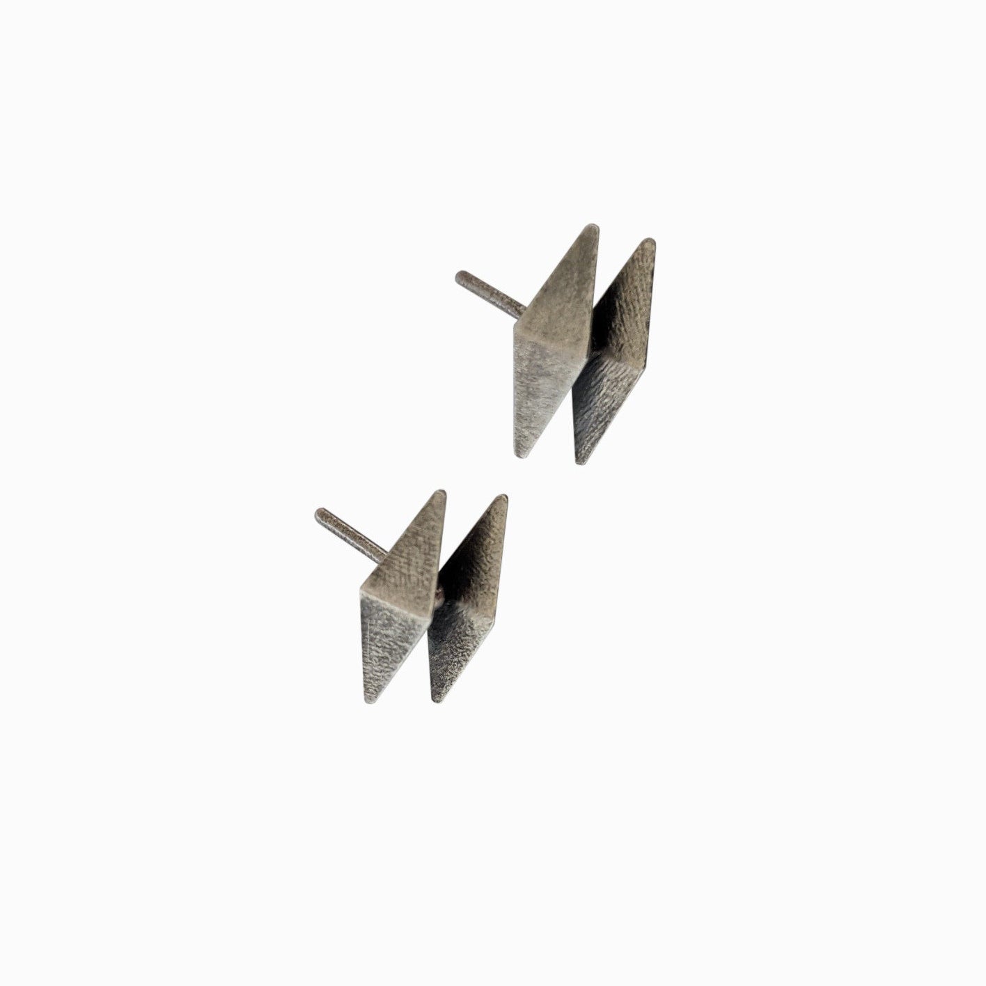 A pair of modern, geometric silver earrings featuring a sharp, angular design, showcased against a minimalist white background.