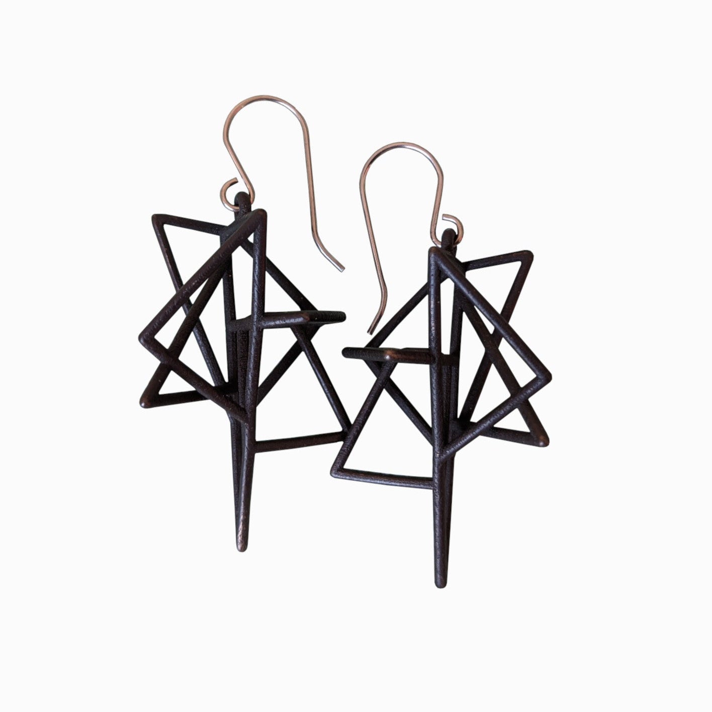 A pair of geometric black earrings featuring intricate triangular designs with pointed ends, hung from silver hooks.