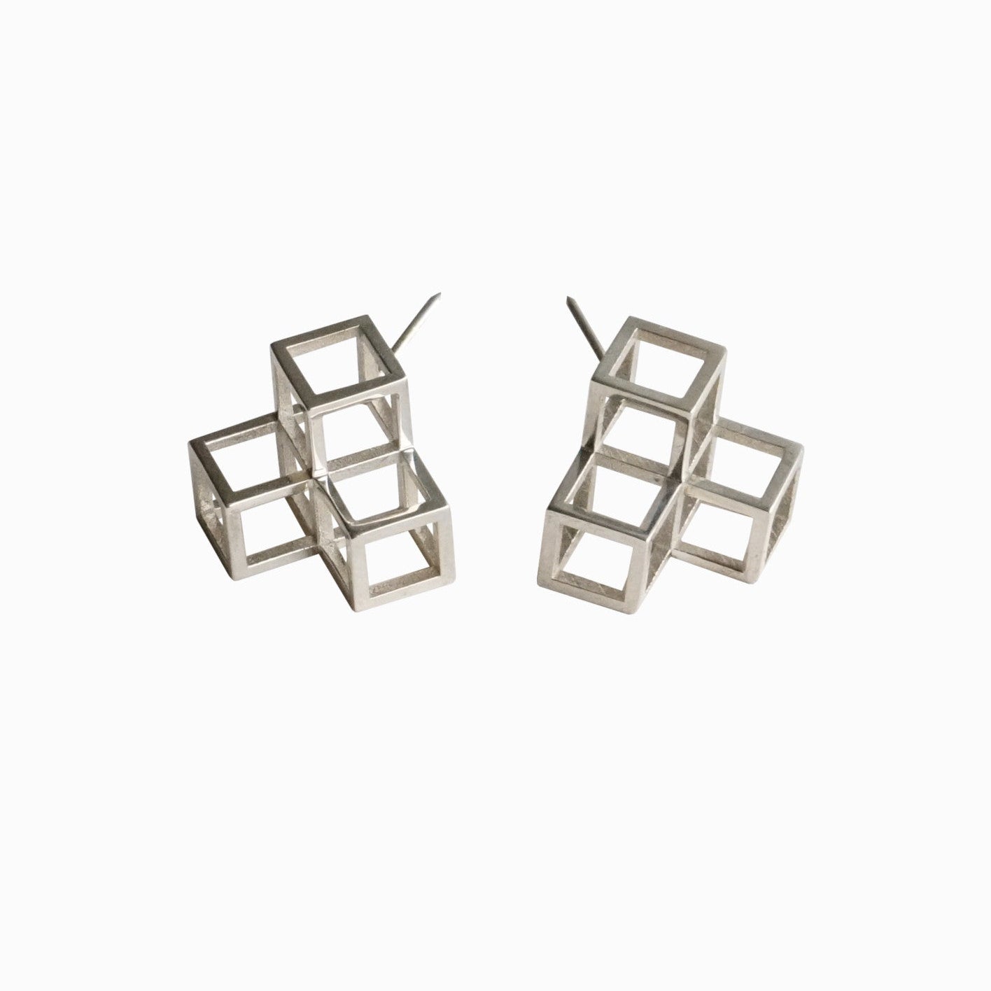 Two geometric silver cube earrings, featuring layered cubes with open framework design, displayed against a white background.