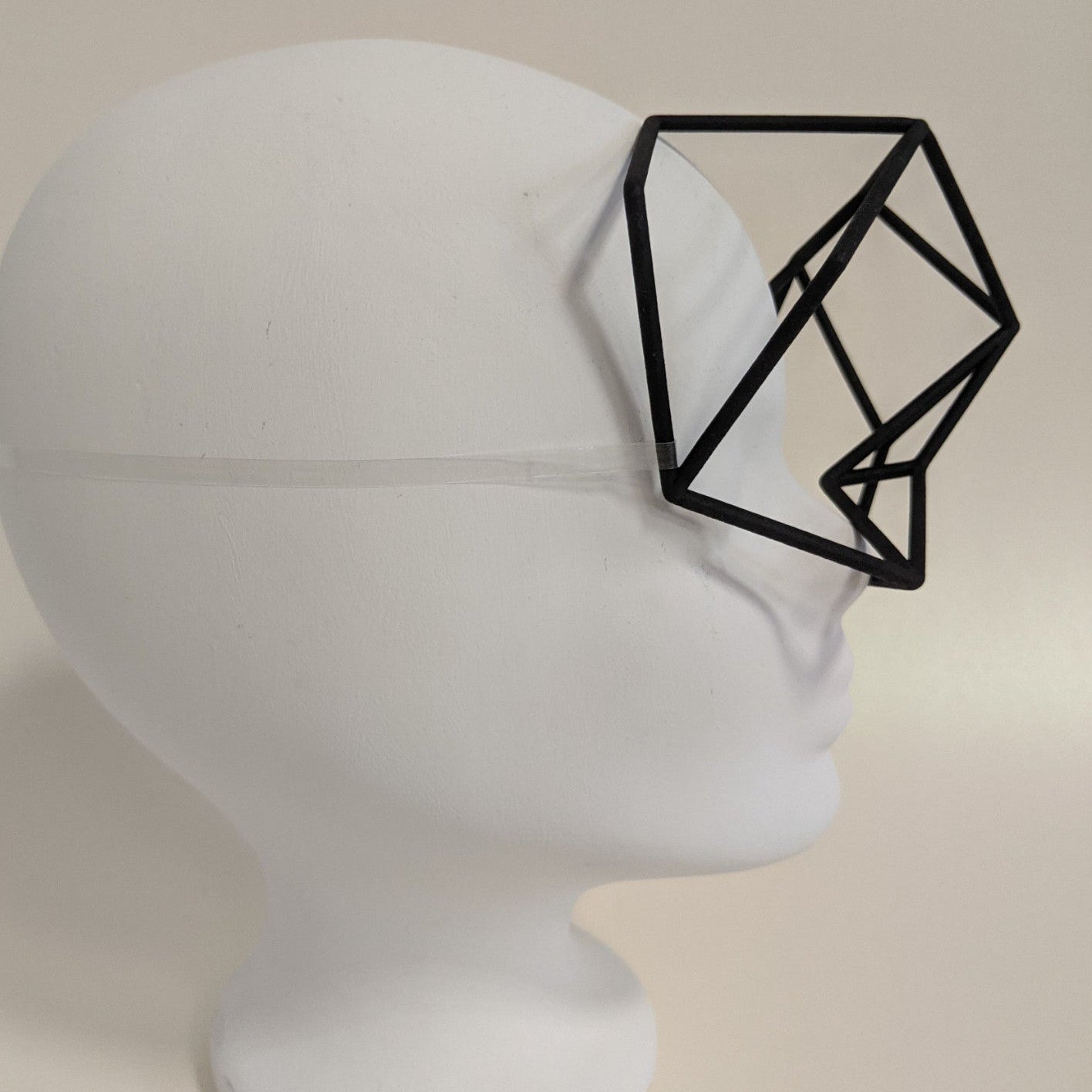 A geometric black frame resembling glasses sits on a white mannequin head, featuring an abstract, polygonal design.