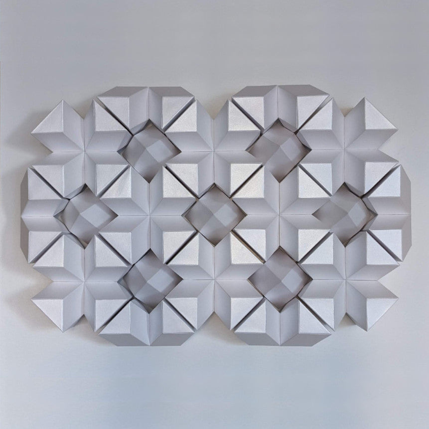 An abstract arrangement of white geometric shapes creates a three-dimensional pattern on a light background.
