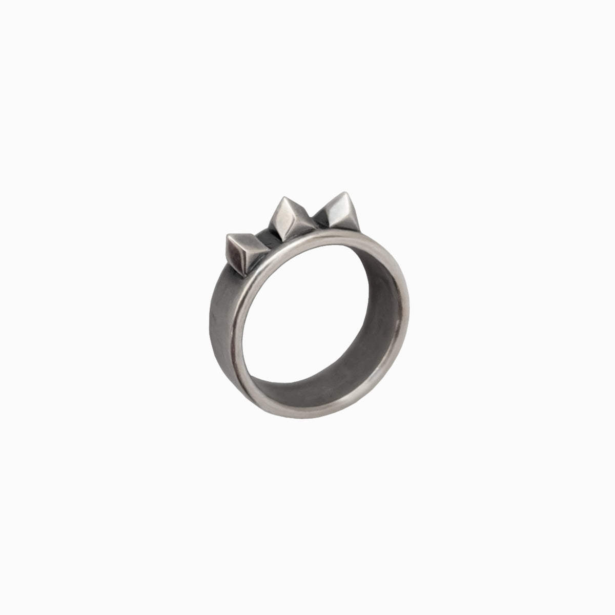 A silver-toned metal ring with a wide band and three small pyramid shapes on top, shown against a plain white background.