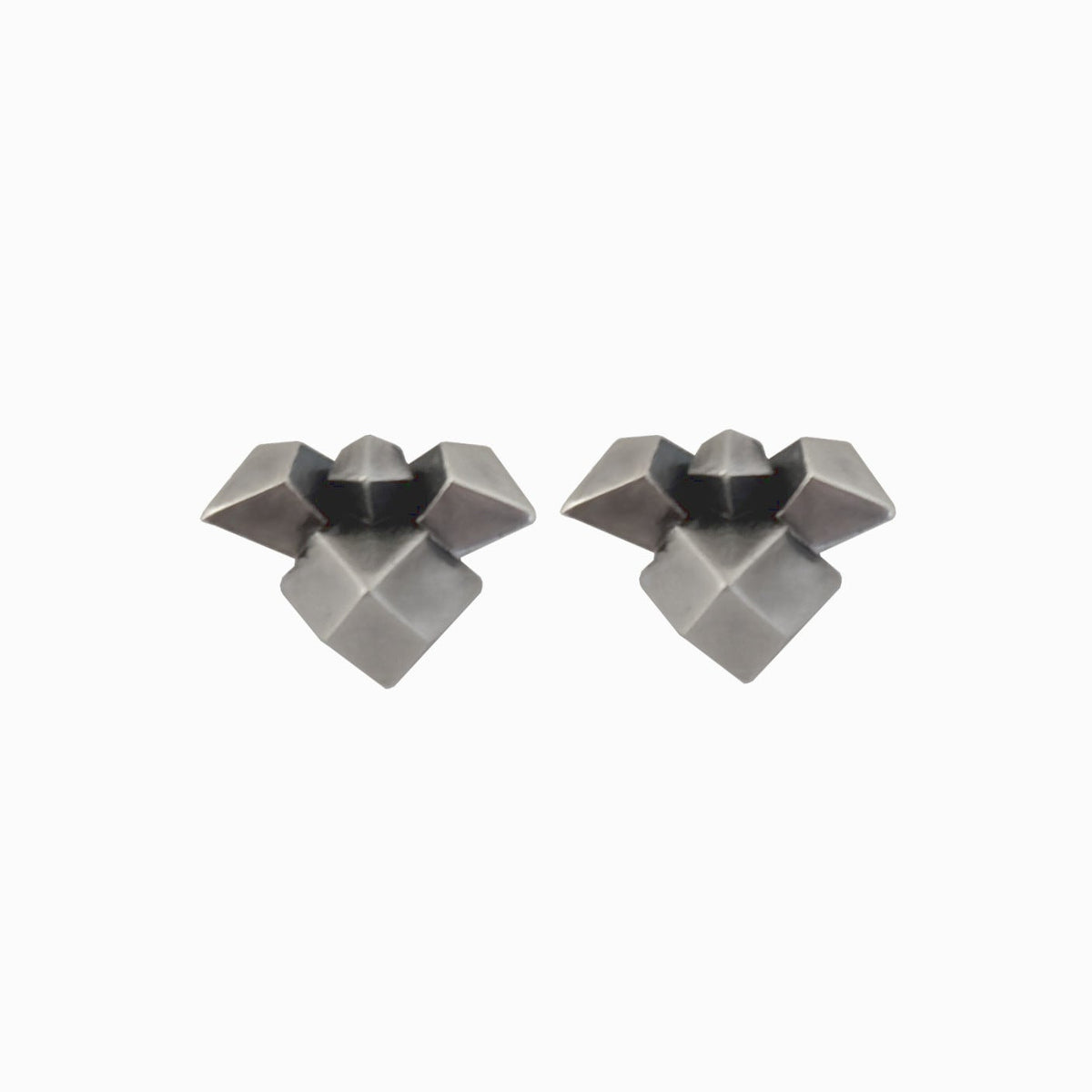 A pair of geometric stud earrings in a matte dark gray metal, featuring a multi-faceted starburst design, shown on a plain white background.