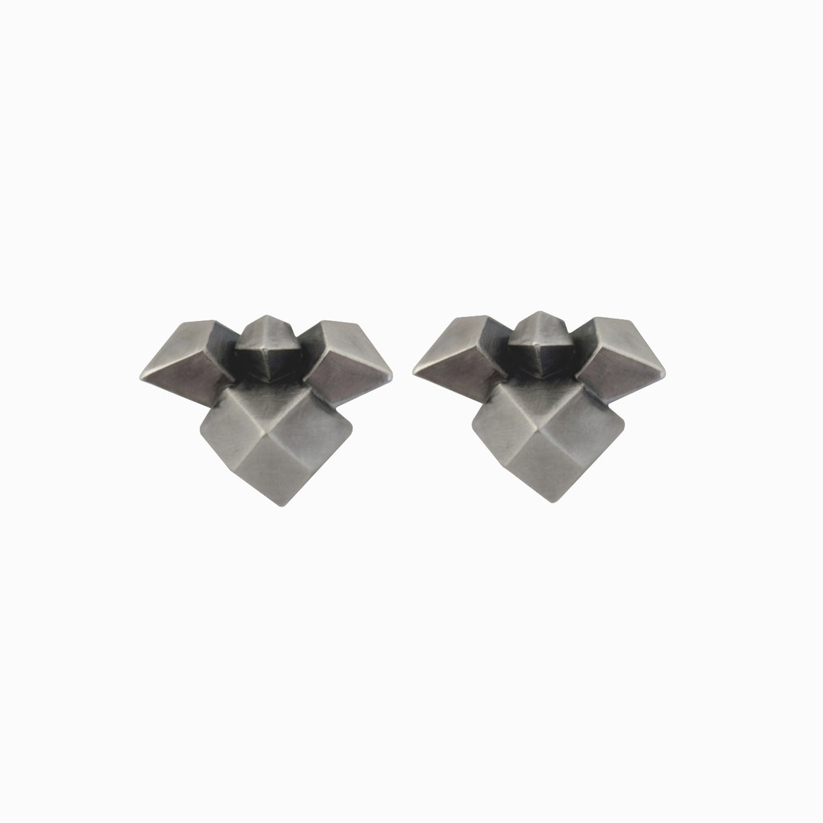 A pair of geometric stud earrings in a matte dark gray metal, featuring a multi-faceted starburst design, shown on a plain white background.