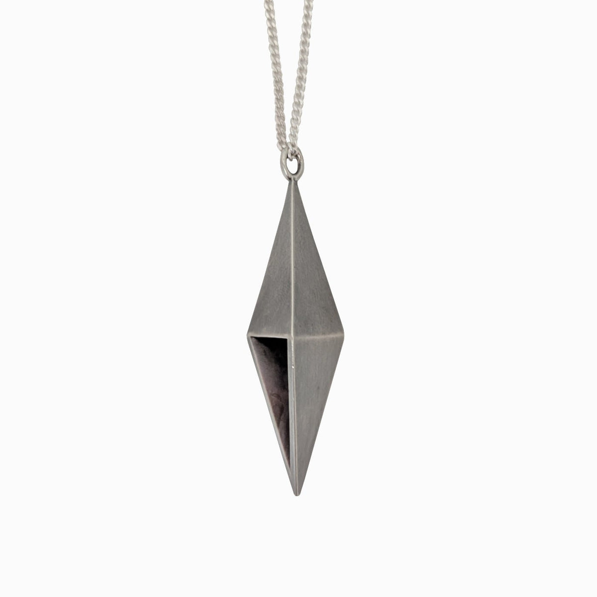 A silver geometric pendant necklace featuring a faceted diamond-shaped charm suspended from a delicate silver chain, set against a plain white background.