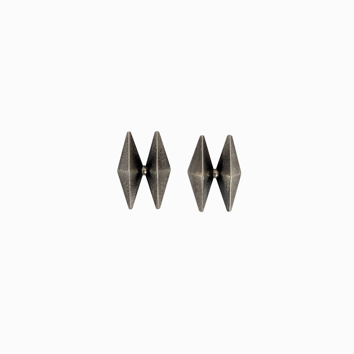 A pair of modern, geometric silver earrings featuring a sharp, angular design, showcased against a minimalist white background.