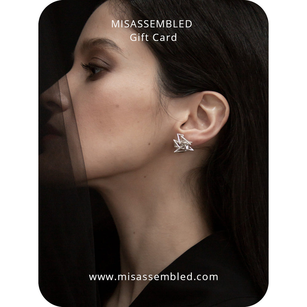 Close-up of an ear adorned with striking silver earrings, showcasing contemporary design against a dark backdrop.
