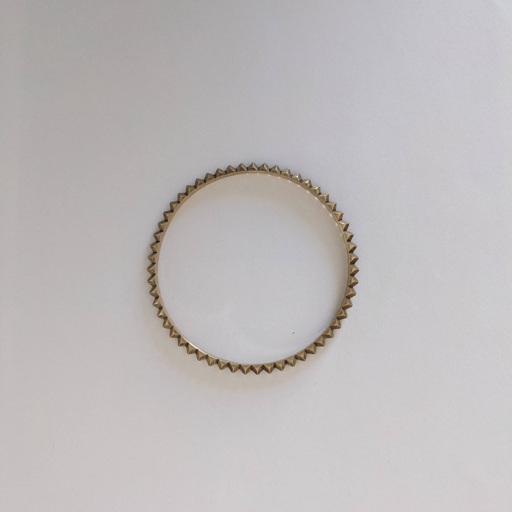 
                  
                    Brass bracelet with a textured design on a white background.
                  
                