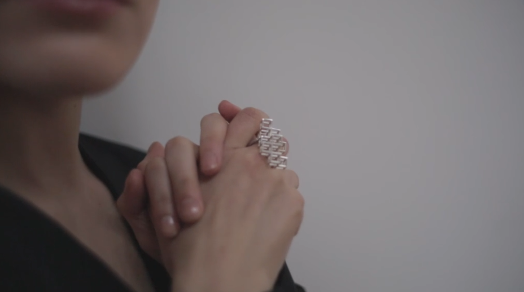 A close-up of a woman's hands wearing a geometric ring as she gracefully moves them around. 