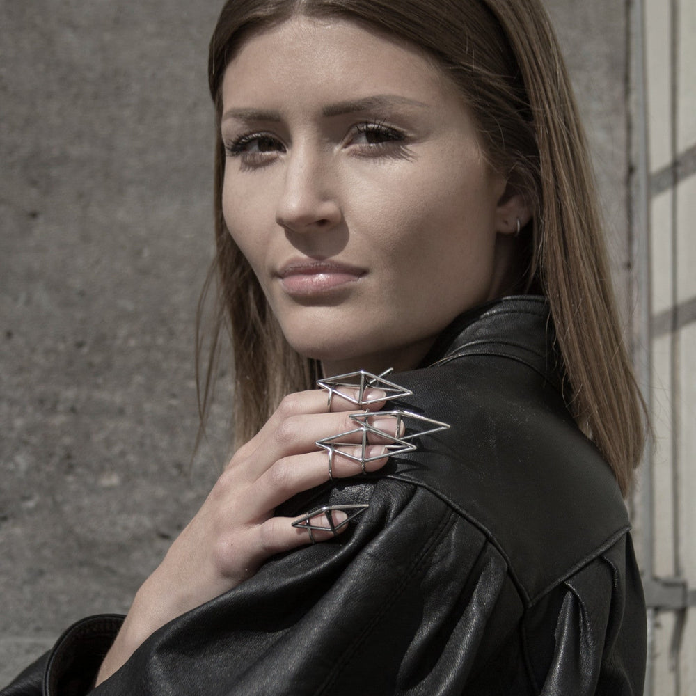 
                  
                    A model in a black leather jacket poses with unique geometric silver nail rings, showcasing a stylish and edgy fashion statement.
                  
                