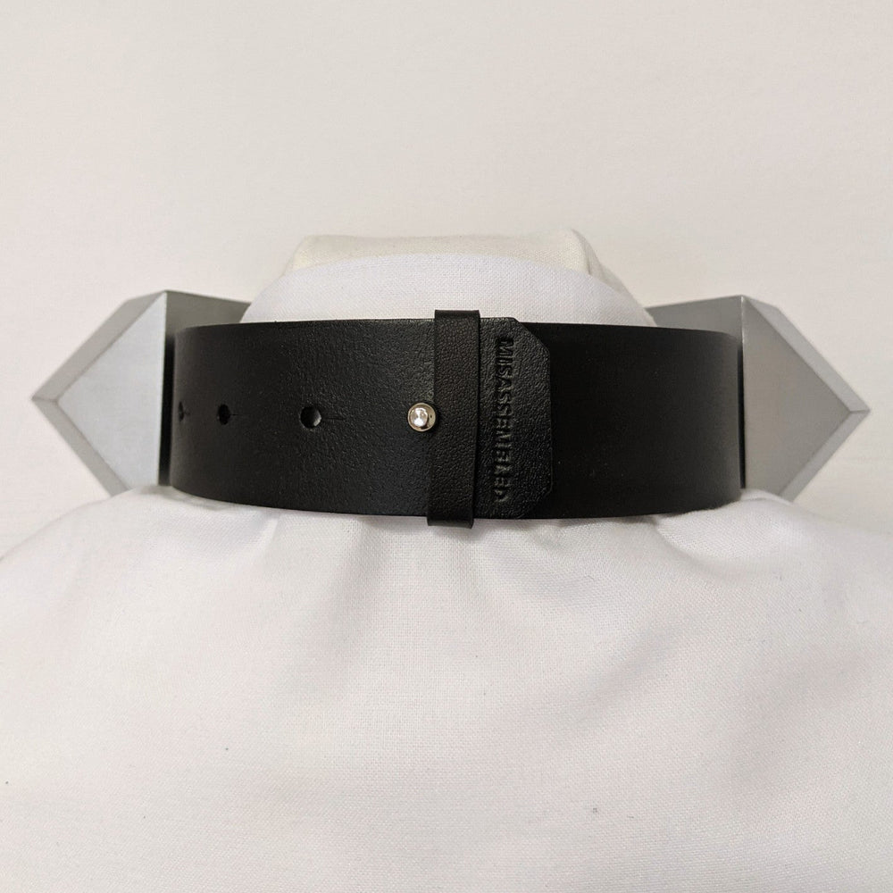 
                  
                    A black leather collar with a silver stud and branded label displayed on a white mannequin, featuring angular metallic accents.
                  
                