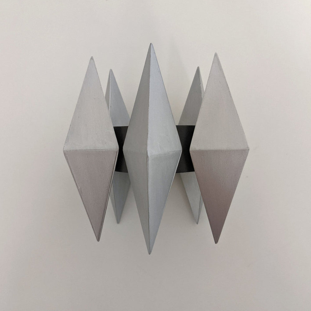 A geometric sculpture featuring four metallic pyramids arranged symmetrically around a central axis.