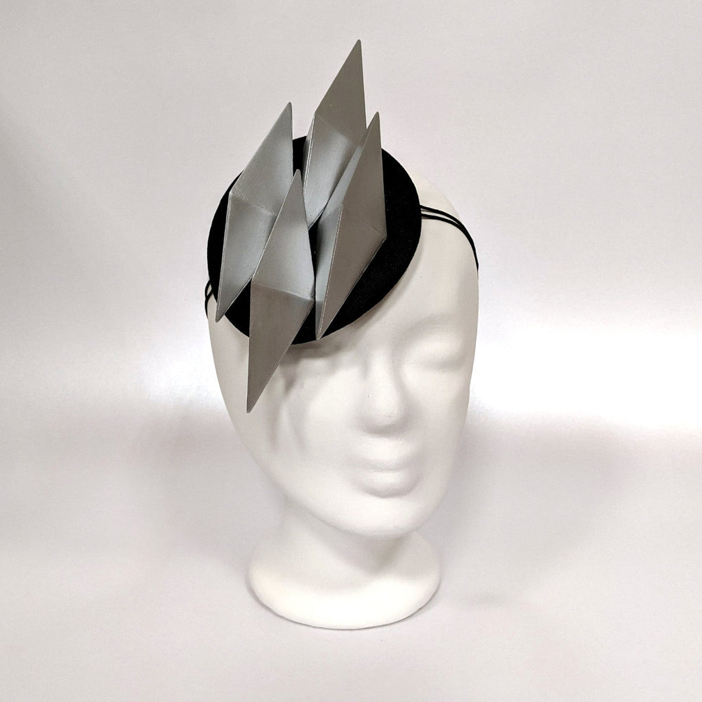 A black headband features three metallic silver triangular spikes, presented on a white mannequin head against a light background.
