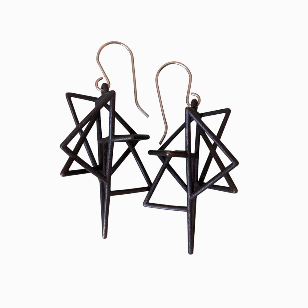 A pair of geometric black earrings featuring intricate triangular designs with pointed ends, hung from silver hooks.
