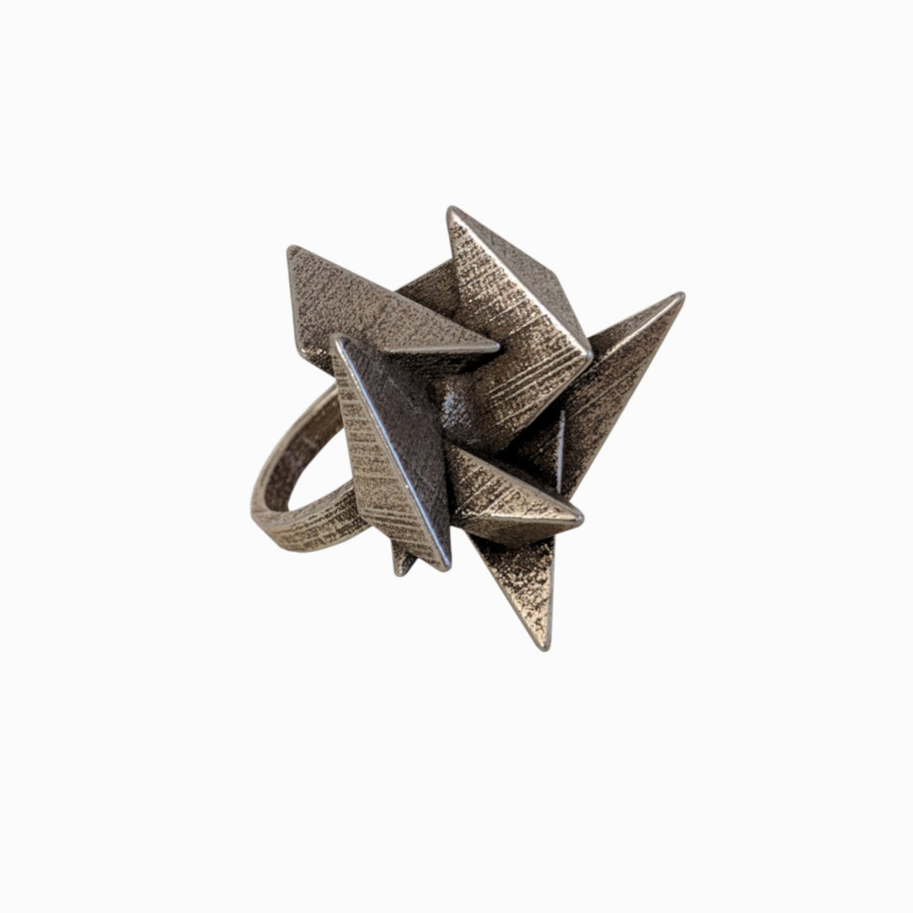 A unique, sculptural ring featuring a cluster of metallic triangular spikes in an artistic, abstract design.