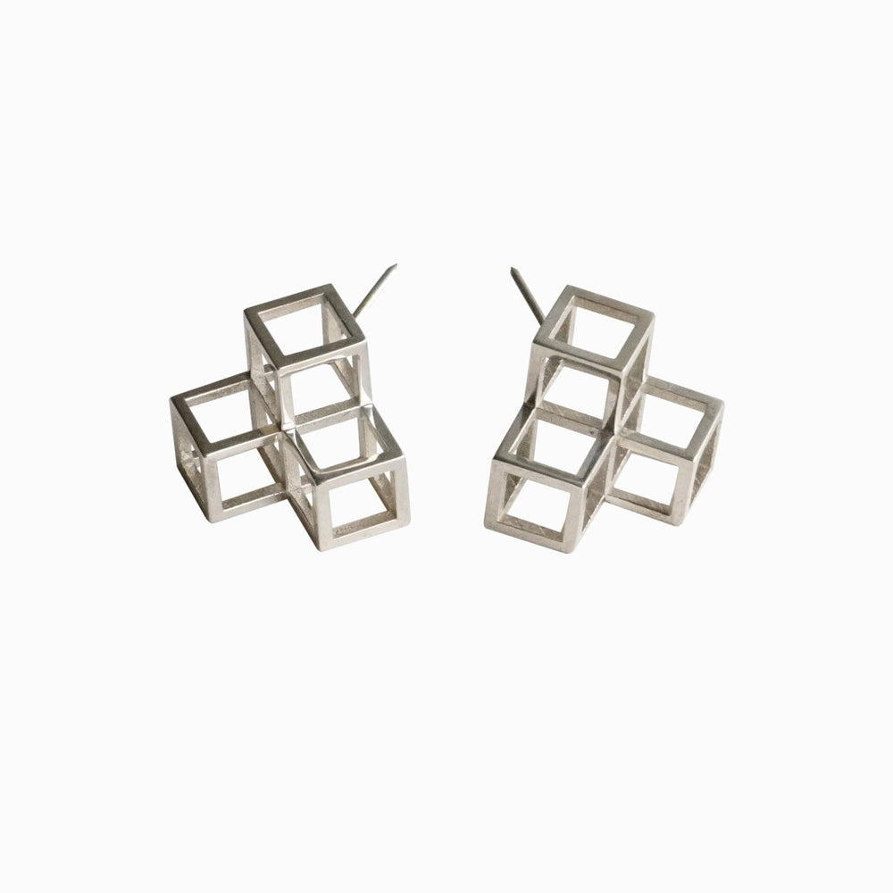 Two geometric silver cube earrings, featuring layered cubes with open framework design, displayed against a white background.