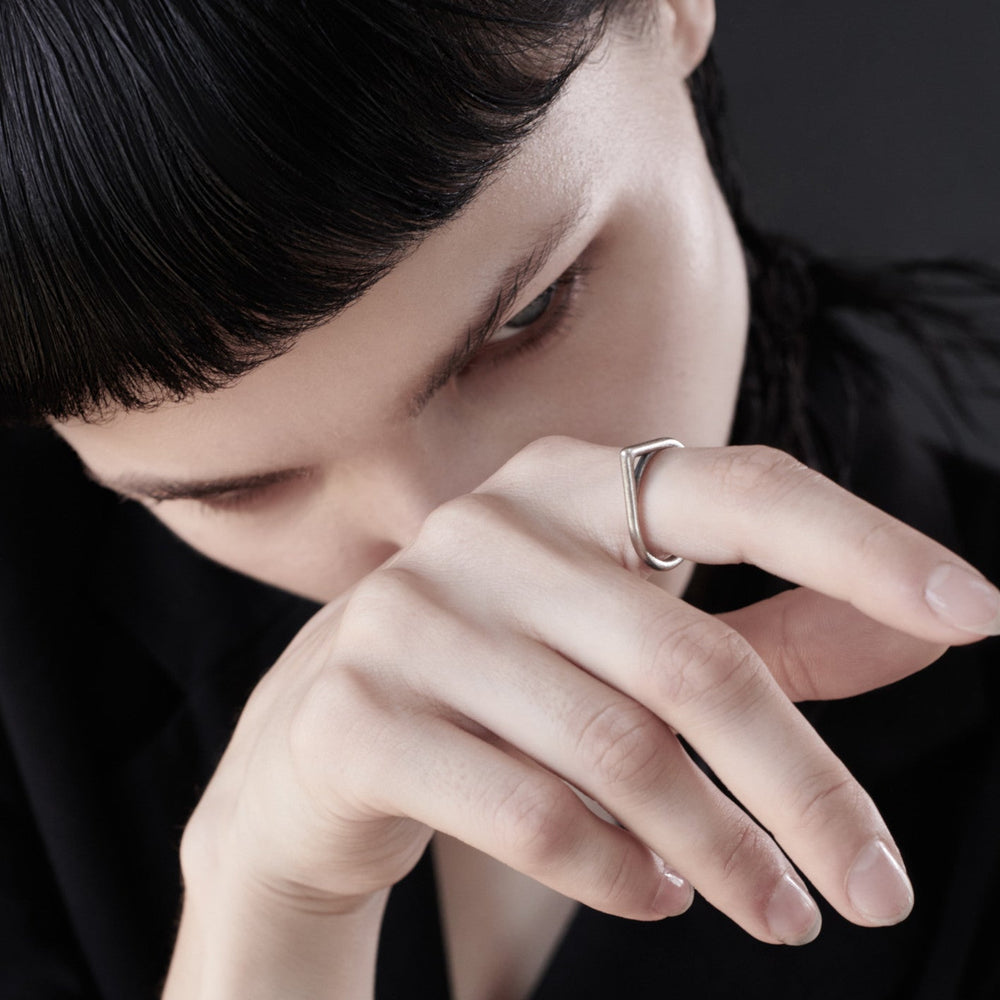 
                  
                    A close-up of hands with elegant, manicured nails resting wearing a silver ring against a dark backdrop, exuding sophistication and mystery.
                  
                
